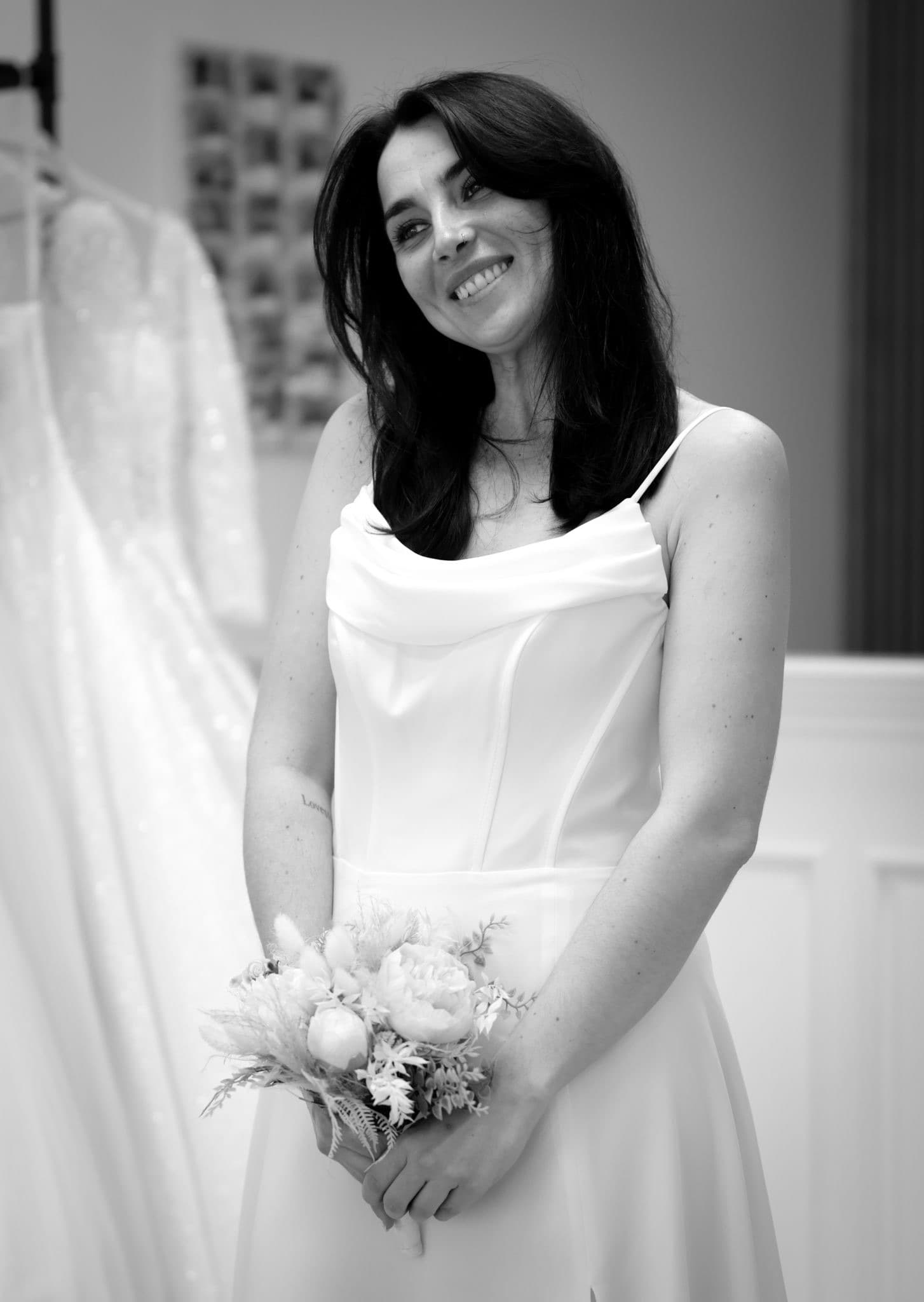 Braut im schlichten Satin-Brautkleid mit Blumenstrauß — Second-Hand-Brautmode Königsbach-Stein