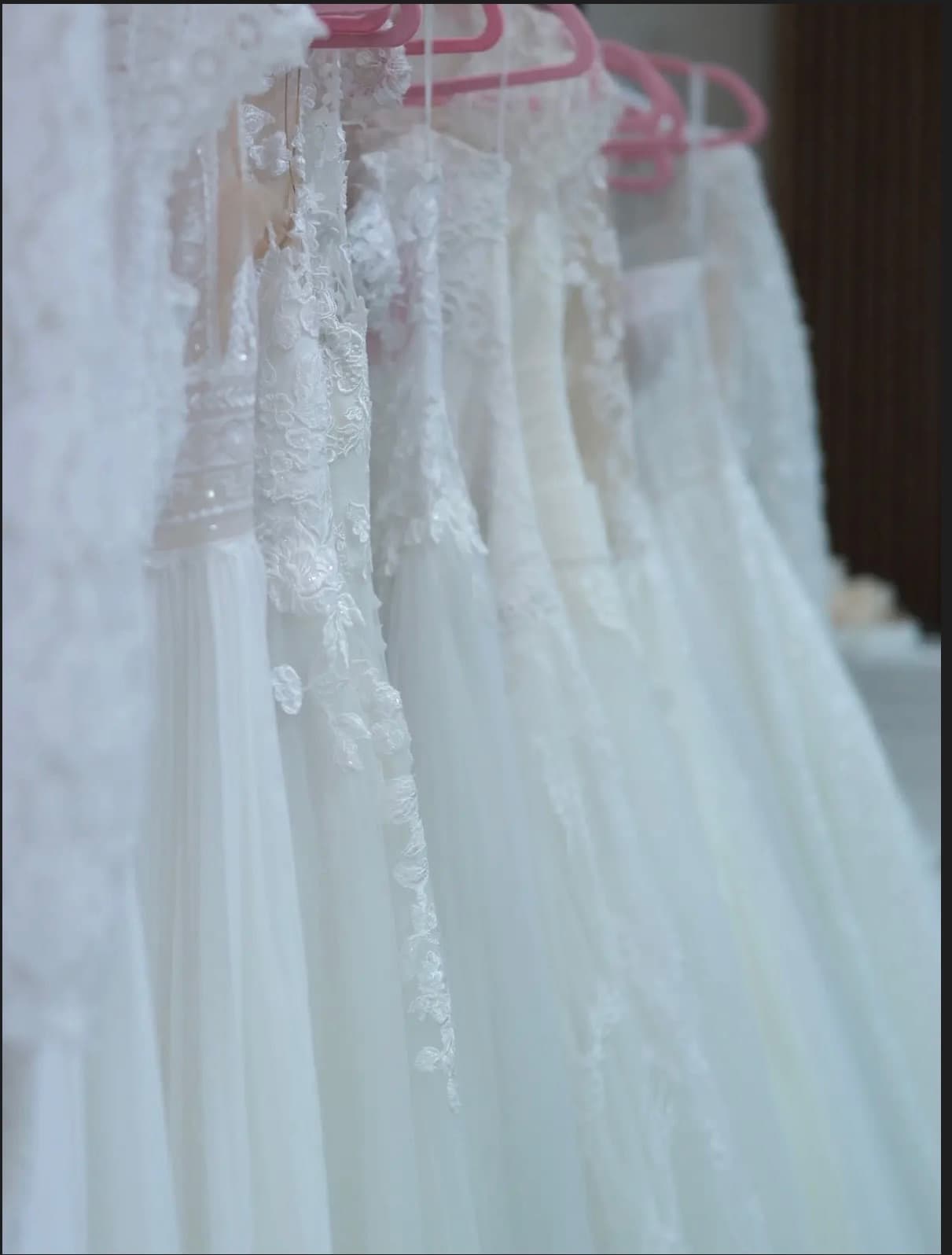 Brautkleider-Kollektion auf Kleiderstange mit rosa Bügeln — Outlet-Brautkleider Liebesgeschichte